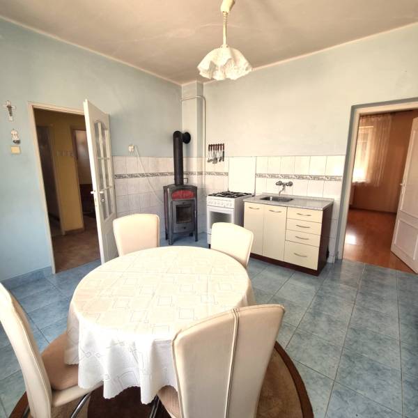 A dining room with a round table and a tiled stove in a family house.