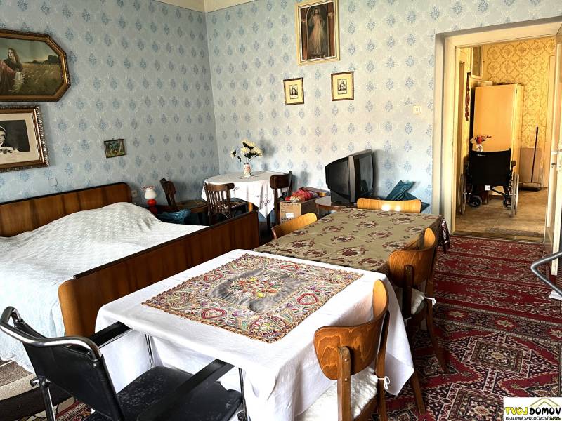 Interior of a family house with a bed, table, and television, a space with traditional decorations.