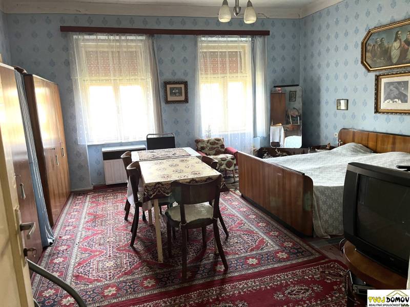 A bedroom in a family house with wooden furniture, a carpet, and wall decorations.