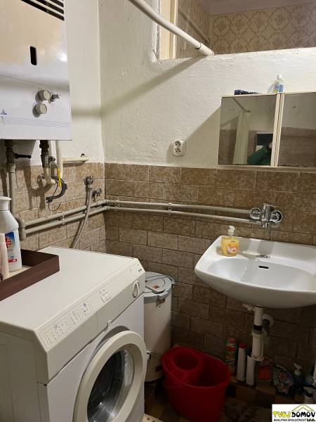 A bathroom in a family house with a washing machine, a sink, and a gas boiler.