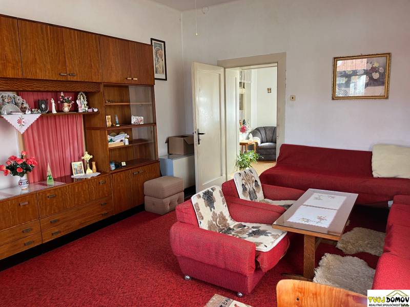 Living room in a family house with a red carpet and wooden furniture.