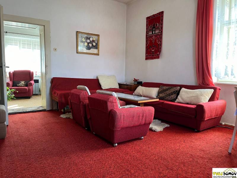 Living room in a family house with a red carpet, sofa, and armchairs.