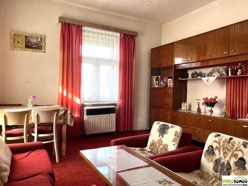 Living room of a family house with a red carpet, curtains, and furniture.