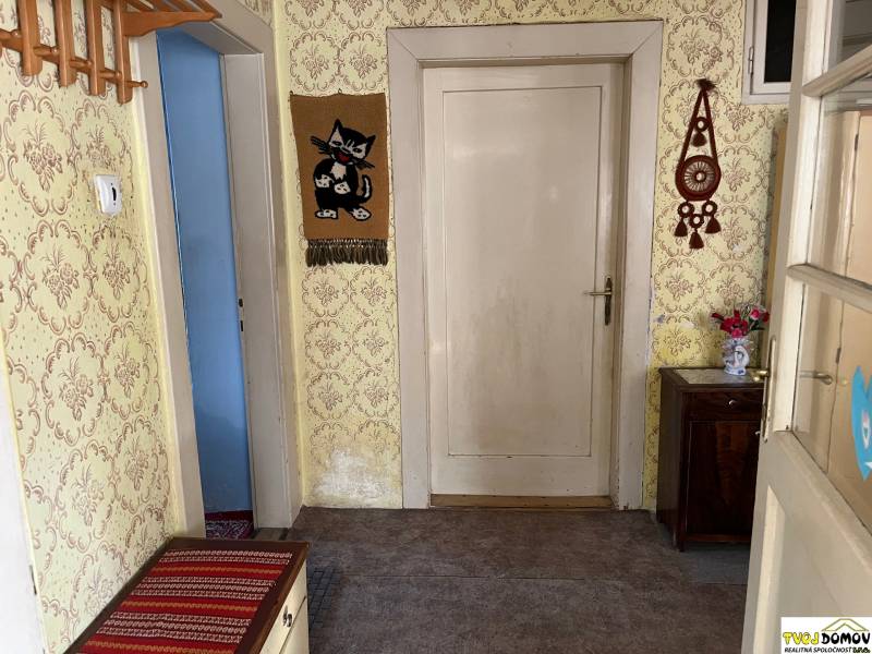 Hallway in a family house with wallpaper, wooden furniture, and wall decorations.