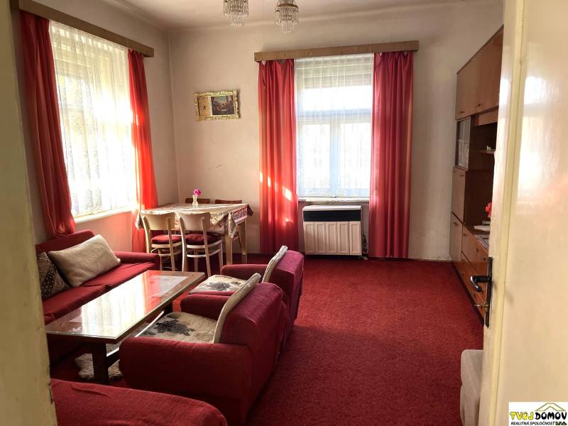 Living room in a family house with red curtains, armchairs, and a table.