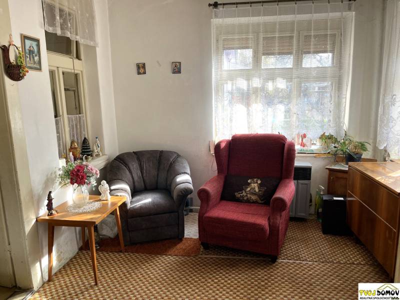 A living room corner with an antique chair and a flower table in a family house.