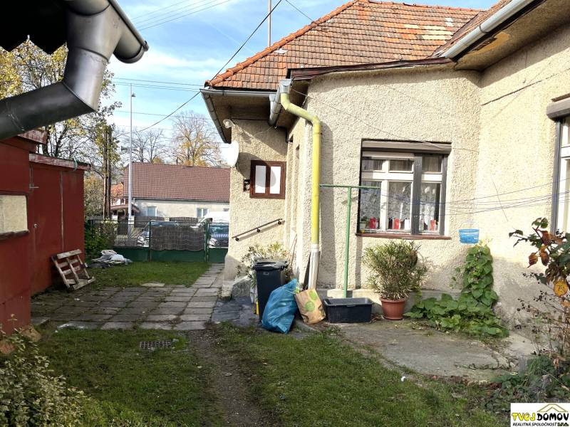 A family house on Partizánska Street in Detva with a yard, plants, and drainage pipes.