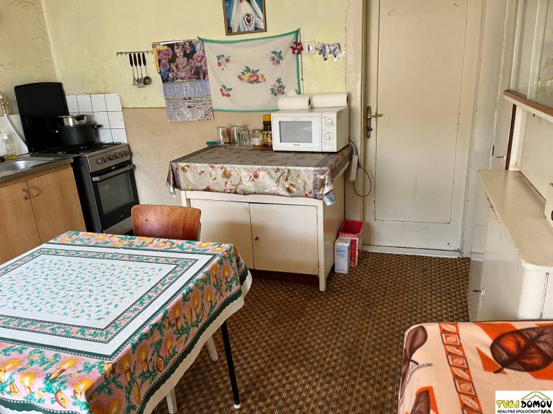 A kitchen in a family house, with a stove, microwave, and a floral tablecloth on the table.