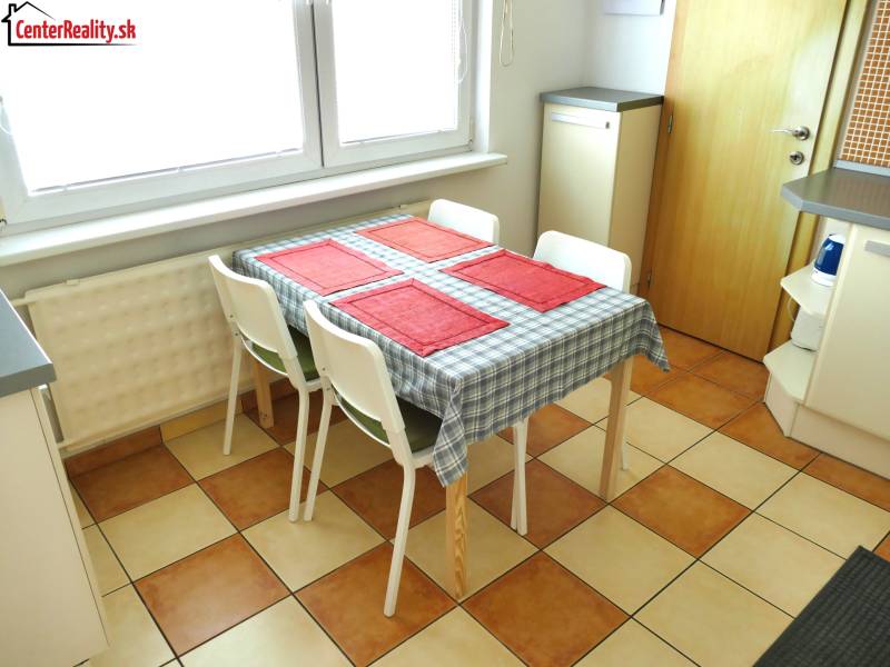 Dining room with a wooden table and four chairs in a three-room apartment, checkered floor.