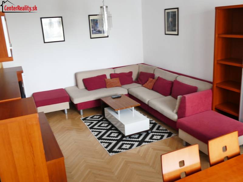 A living room of a three-room apartment with a corner sofa and wooden furniture.