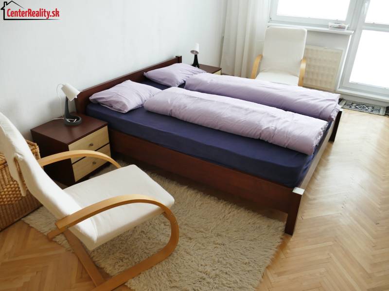 A bedroom in a 3-room apartment with a double bed, comfortable chairs, and a light carpet.