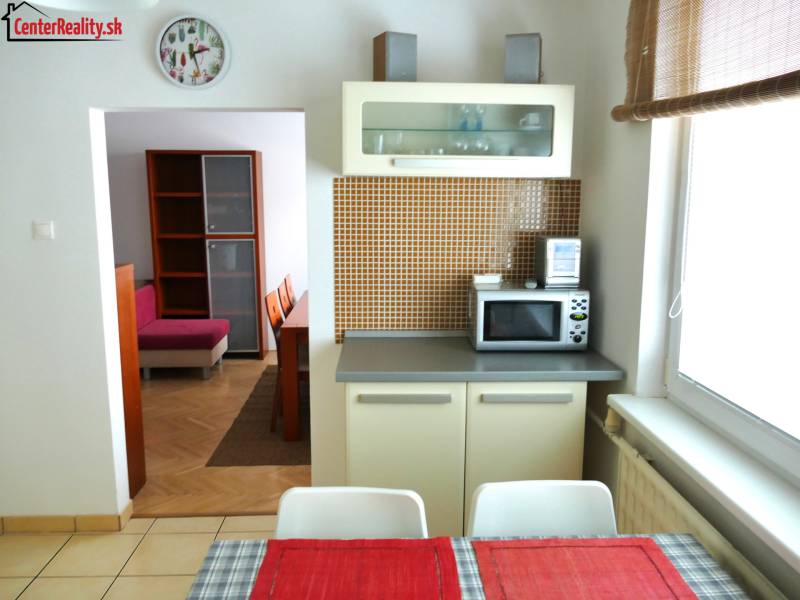 A kitchen in a 3-room apartment with a dining table and a view into the living room.