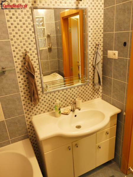 A bathroom with a sink and a mirror in a three-room apartment, tiled with blue and blue-white tiles.