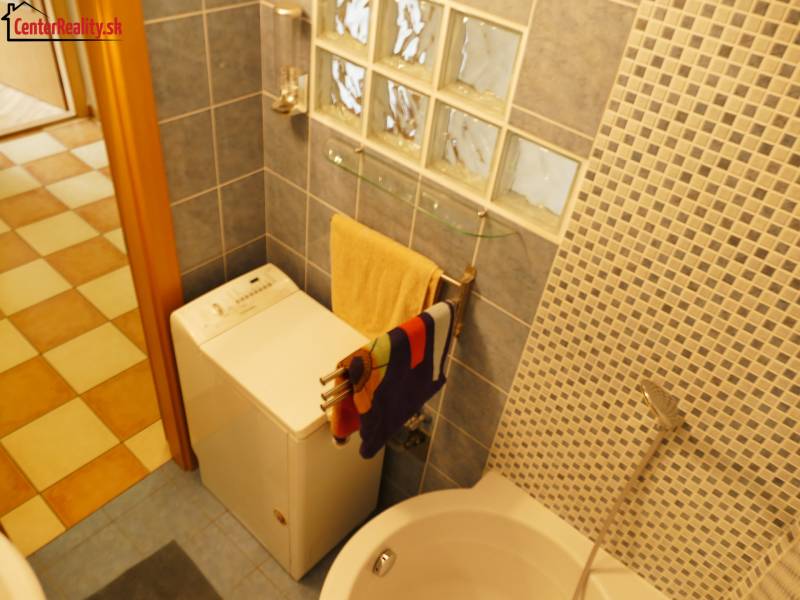 A bathroom in a 3-room apartment with a washing machine, a bathtub, and a mosaic tiled wall.