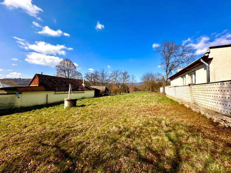 Construction of houses in Moravské Lieskové, showing grassy plots and surrounding buildings.