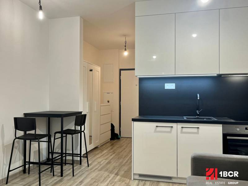 A kitchen in a studio apartment with minimalist equipment and a dining nook.