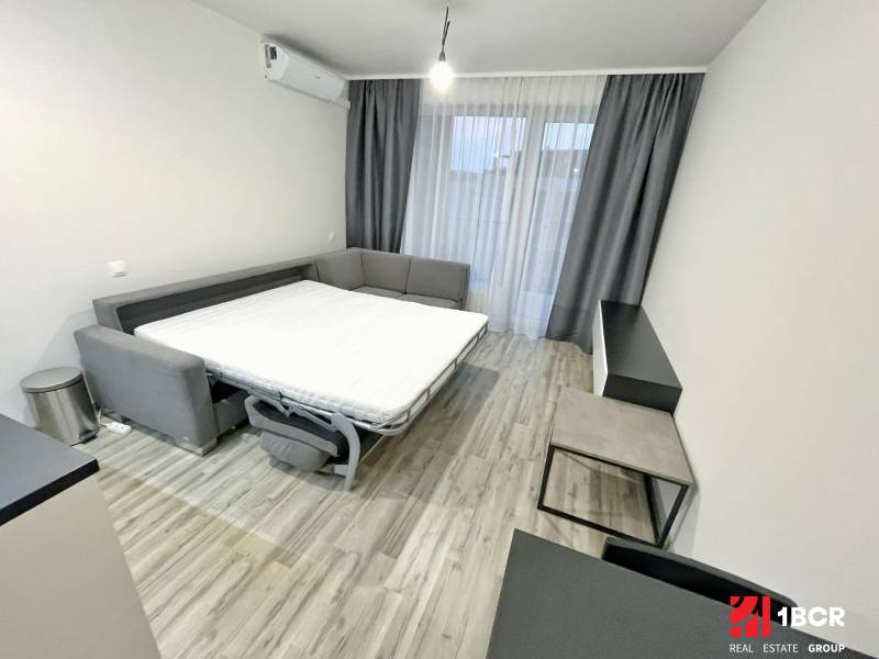 1-bedroom apartment with a sofa bed, air conditioning, and curtains on large windows.