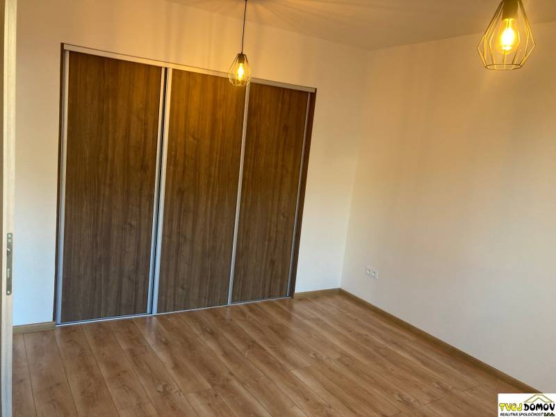 A room in a 3-room apartment with a wooden floor and a built-in wardrobe, light from the chandelier.