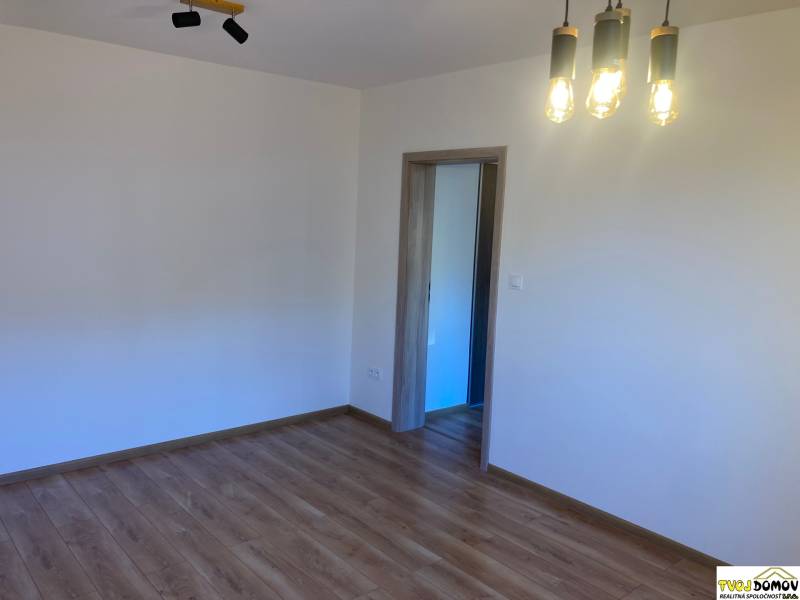 A room with pendant lighting and wooden flooring in a 3-room apartment.