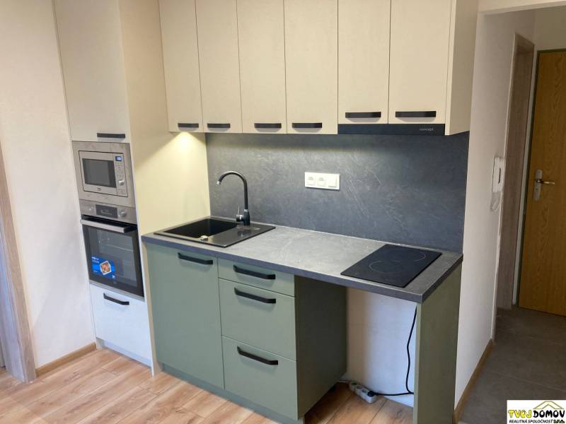 A kitchen in a 3-room apartment with a combination stove and gray cabinets.