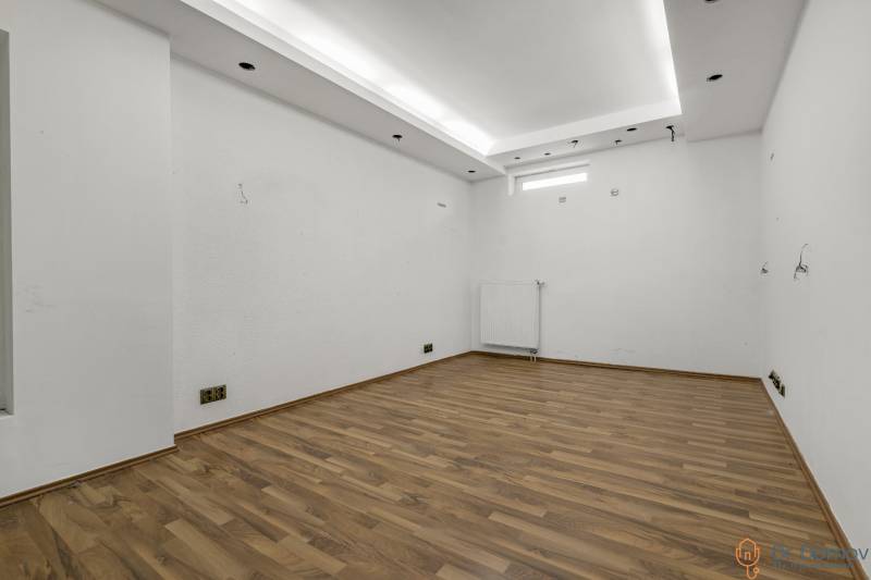 Empty commercial spaces with white walls and wooden flooring.