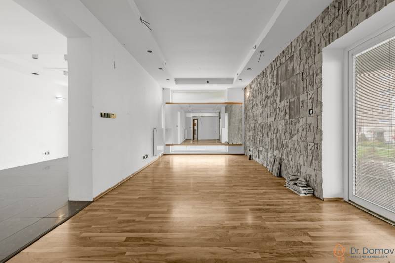 Commercial premises with wooden flooring and a stone wall, suitable for various uses.
