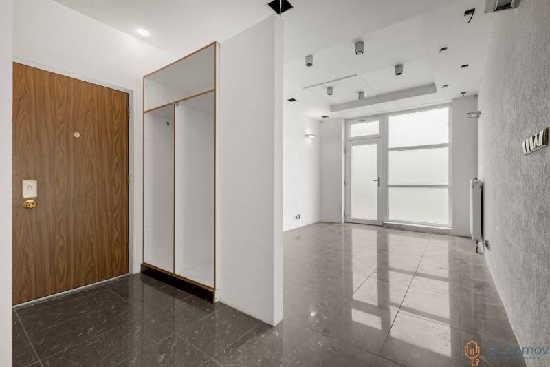 Commercial premises with entrance wooden doors, a cabinet, and large glass doors.