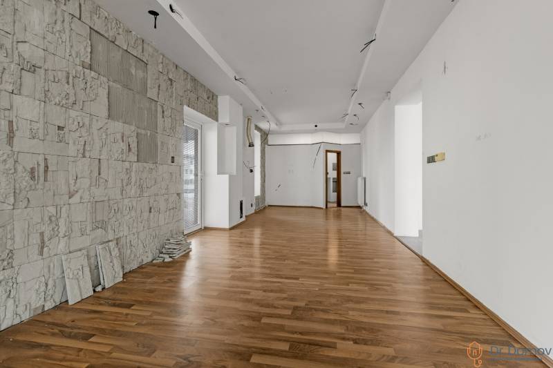 Interior of commercial spaces with wooden flooring and textured wall.