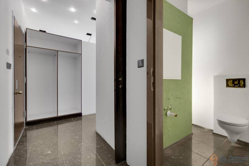 A corridor with tiles and a built-in wardrobe leading to a bathroom in commercial premises.