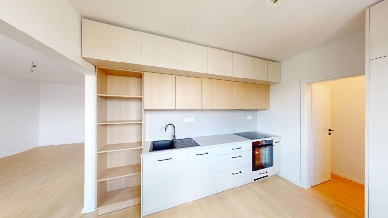 A kitchen in a 2-room apartment with white cabinets and a built-in oven.