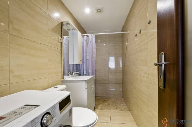 Bathroom in a 2-room apartment with a washing machine, mirror, and shower curtain.