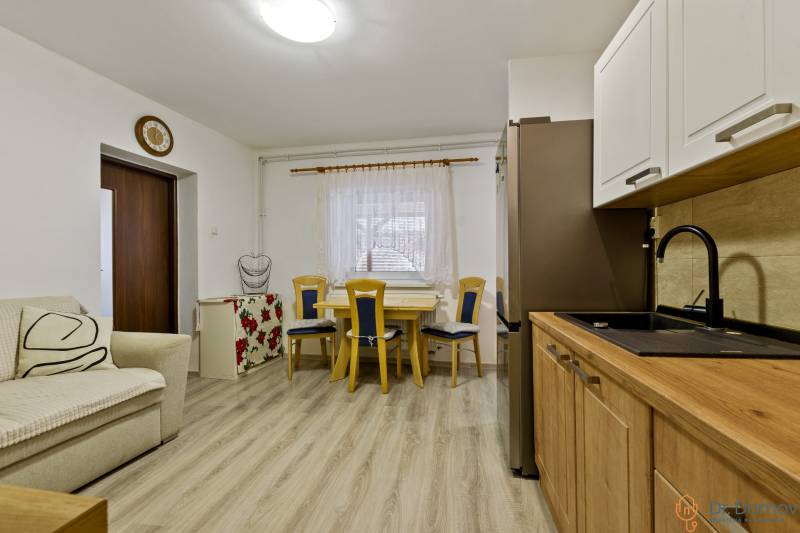 Kitchen and dining area in a 2-room apartment with light furniture and wooden flooring.