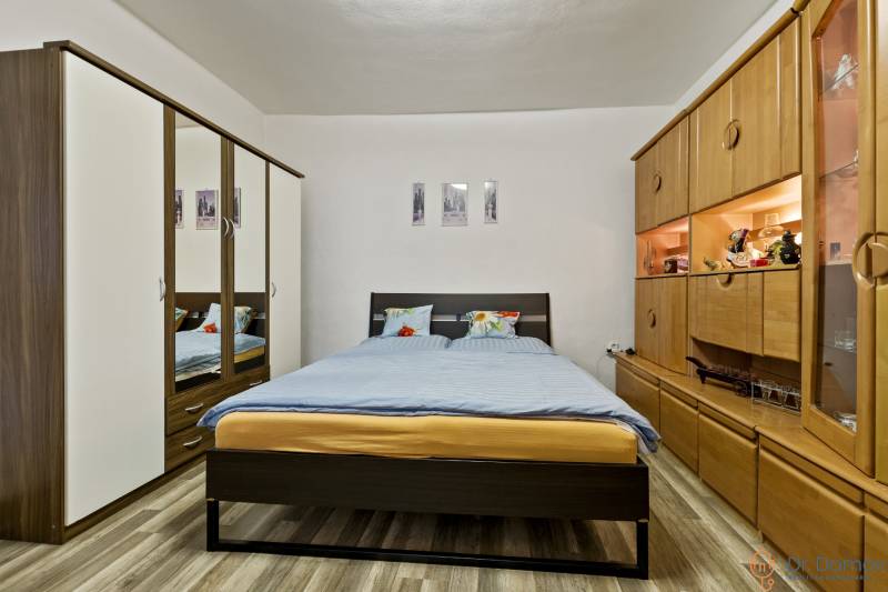 Bedroom in a 2-room apartment with a double bed, built-in wardrobe, and wooden wall unit.