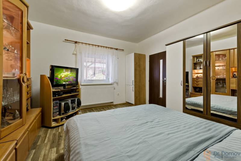 A bedroom in a 2-room apartment with a bed, wardrobe, TV, and wooden furniture.