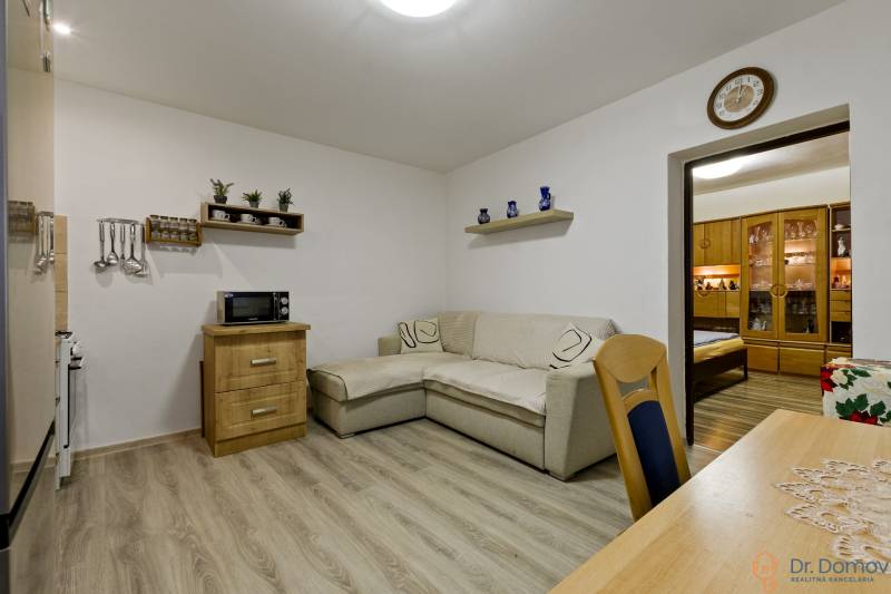 Living room with a sofa, wooden furniture, and shelves in a 2-room apartment.