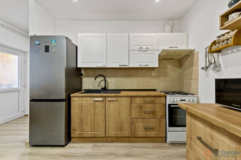 A kitchen with a stove and a refrigerator in a 2-room apartment.