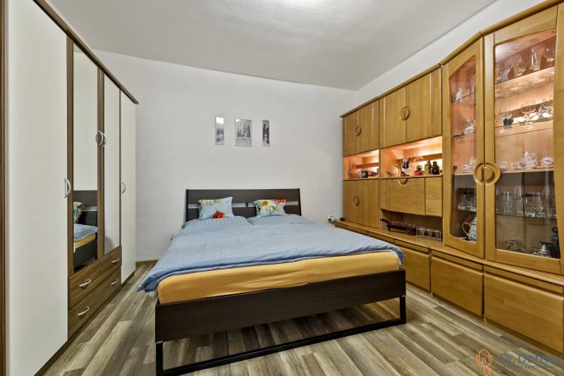 A bedroom in a 2-room apartment with a double bed, wardrobes, and a decorative shelving system.