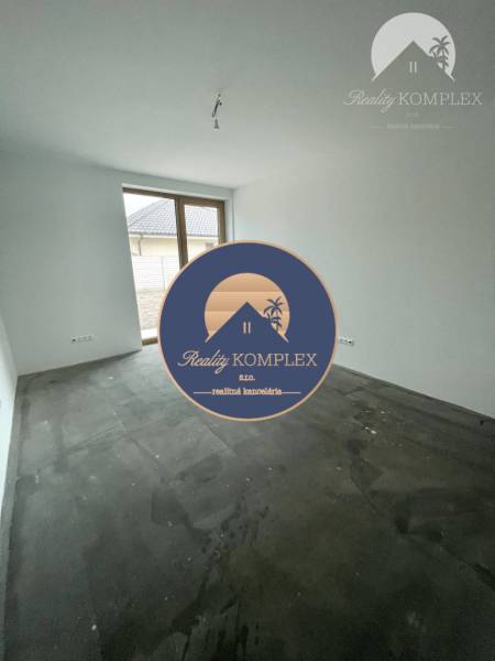 An empty room with a large window in a family house, with an unfinished floor.