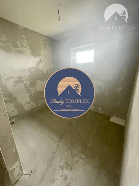 A room in a family house with bare walls, a small window, a light source without a lampshade.