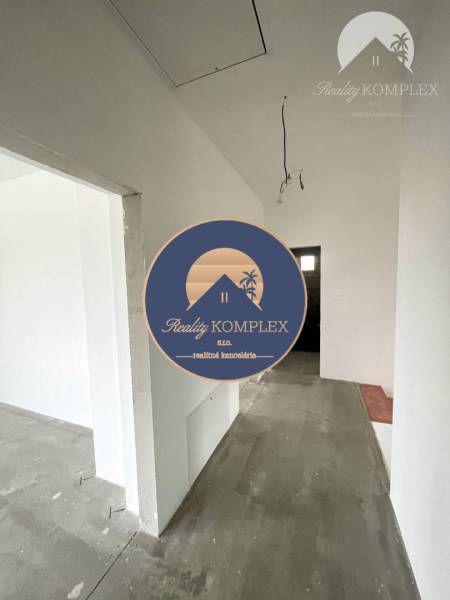 A hallway in a family house with white walls and a concrete floor.