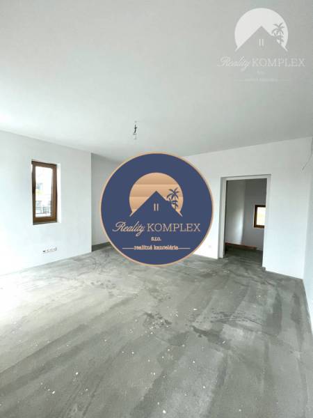 A spacious room in a family house with a concrete floor and white walls.