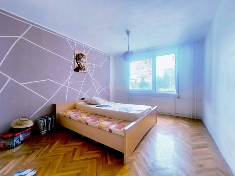 A bedroom in a 3-room apartment with wooden flooring and striking wall decoration.