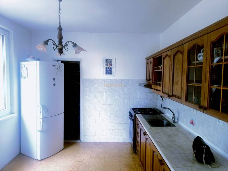 A kitchen in a 3-room apartment with rustic wooden cabinets and a white refrigerator.