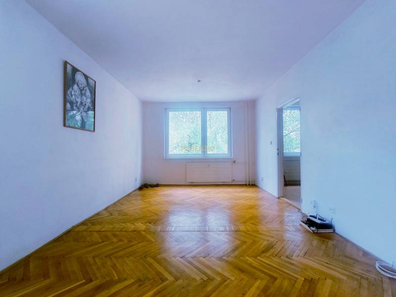 A spacious room with wooden flooring and a painting on the wall in a 3-room apartment.