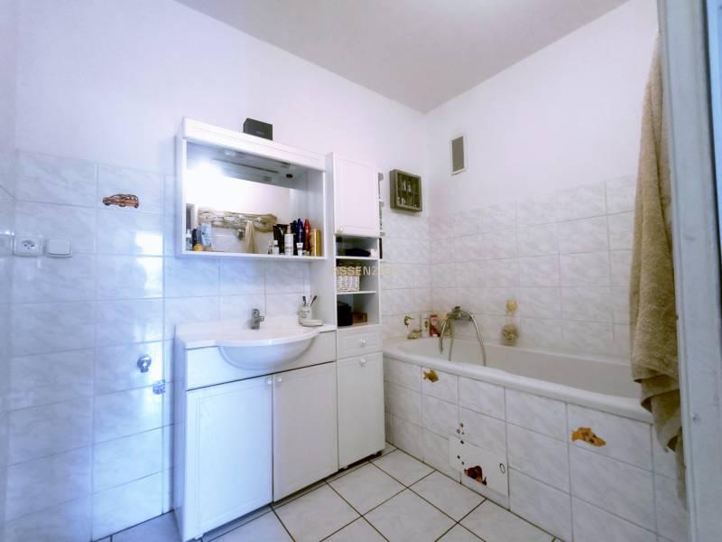 A bathroom in a 3-room apartment with a bathtub, sink, and storage space.