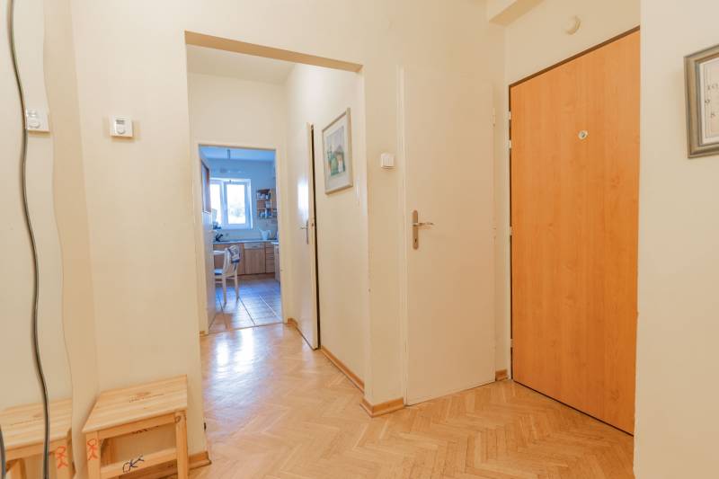 A hallway with an entrance to the kitchen, wooden decor flooring, in a 4-room apartment.
