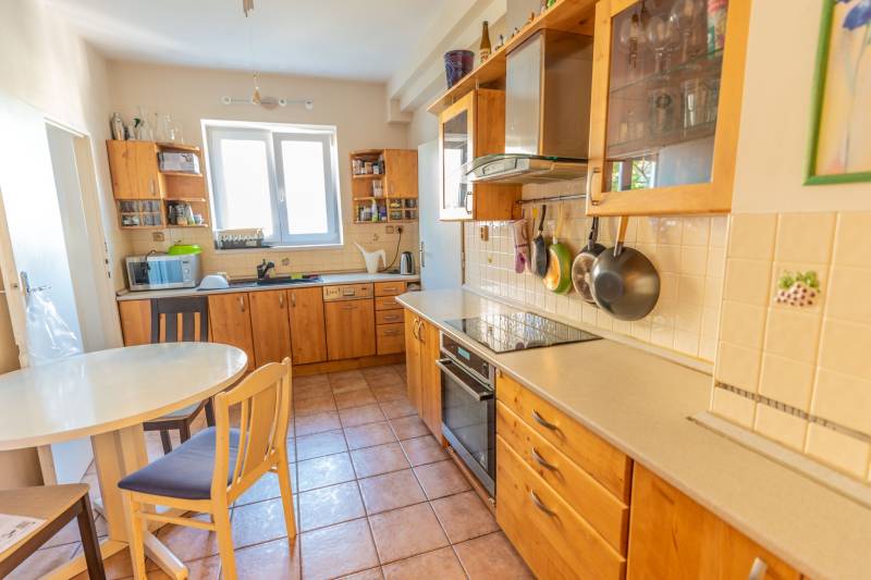A kitchen in a 4-room apartment with wooden cabinets, a table, and ceramic tiles.