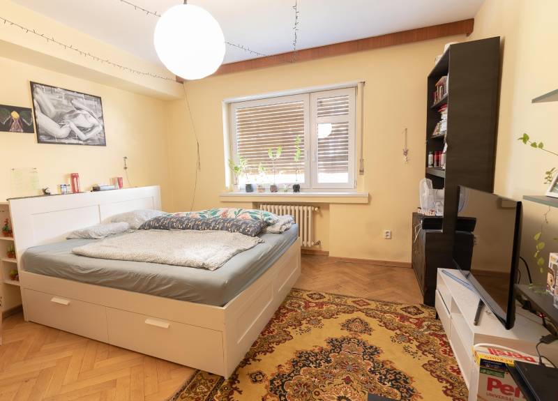Bedroom in a 4-room apartment with a bed, carpet, and floor with wooden decor.