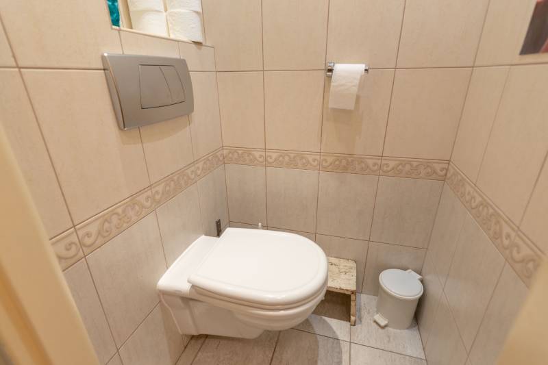 A toilet with light tiles and folding doors in a 4-room apartment.