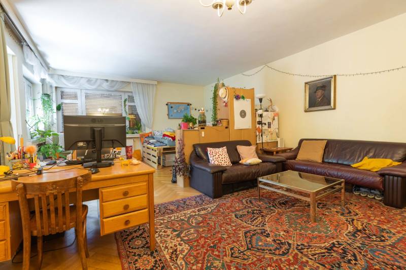 Living room in a 4-room apartment with a sofa, carpet, and desk.